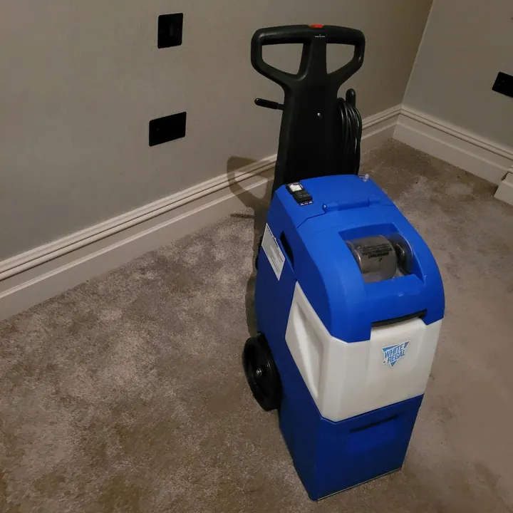 Professional carpet cleaning machine on a freshly cleaned bedroom carpet